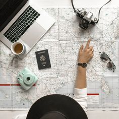 a person sitting at a table with a map, camera, laptop and other items