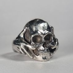 **Please note we dispatch weekly on Tuesdays**  Large sterling silver skull in hands ring This is a beautiful large ring! Weighty and a real statement piece.  Original design carved in wax then lost wax cast into solid recycled sterling silver. Large piece which weighs approximately 28g in silver. Also available blackened/oxidised finish, or in any other precious metal.  IF SELECTING THIS RING IN GOLD PLEASE NOTE THAT GOLD RINGS ARE MADE TO ORDER, ARE NON-RETURNABLE, AND THAT DISPATCH WILL TAKE APPROXIMATELY 8 WEEKS. First class signed for post included, with a supplement for special delivery. Unique Silver Skull Rings, Unique Hand Cast Skull Rings, Symbolic Hand Cast Skull Ring, Unique Sterling Silver Skull Ring With Polished Finish, Gothic Hand Cast Sterling Silver Skull Ring, Hand Cast Gothic Skull Ring In Sterling Silver, Silver Skull Rings Hallmarked, Hand Cast Sterling Silver Skull Ring, Silver Skull Ring With Hallmark