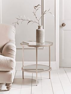 a living room with a chair, table and vase on the floor next to it