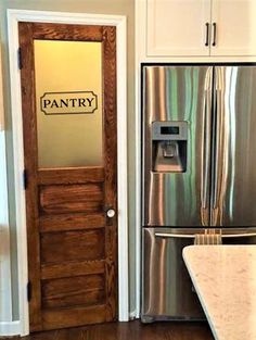 a stainless steel refrigerator and wooden door in a kitchen