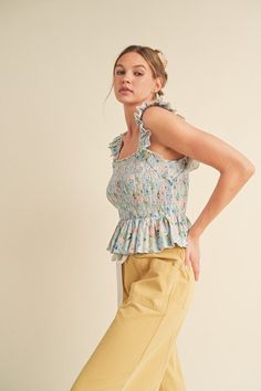 Introducing The Alana Floral Sleeveless Blouse – your new go-to for effortless style + feminine charm. This top features a flattering square neckline, a slightly cropped length + a double ruffle sleeve strap, making it the perfect trendy top to add to your wardrobe. The peplum style with smocked bodice enhances your silhouette. It has a beautiful watercolor floral print that brings a burst of color + feminine look to your wardrobe. Pair it casually with denim shorts for a laid-back summer vibe, Trendy Sleeveless Smocked Top For Spring, Spring Feminine Sleeveless Smocked Top, Feminine Summer Smocked Top With Ruffled Straps, Feminine Smocked Top With Ruffled Straps For Summer, Sleeveless Feminine Smocked Top For Spring, Feminine Sleeveless Smocked Top For Spring, Spring Sleeveless Tank Top With Smocked Back, Spring Ruffled Square Neck Crop Top, Spring Brunch Smocked Top With Ruffled Straps