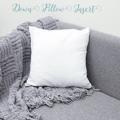 a white pillow sitting on top of a gray couch next to a blanket and pillows