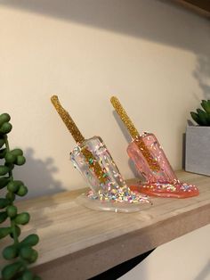 two pink and gold glittered toothbrushes sitting on a shelf next to a succulent plant