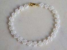 Simple white beaded daisy bracelet. Very dainty and in light colors. The petals are white and the center of the flowers is shiny light cream. The perfect romantic gift for her. You can choose between having an extender chain or not. If you, for example, choose 16cm, the bracelet will be 16cm + 3cm extender chain. The chain and clasp are 24k gold plated brass. Each jewelry item comes in a colorful envelope, as seen in the last picture, and is ready to be gifted. You can find more bracelets here h White Dainty Beaded Bracelet With Flower Charm, Dainty White Beaded Bracelet With Flower Charm, White Dainty Flower Shaped Beaded Bracelets, Delicate White Flower Beaded Bracelets, Delicate White Flower Shaped Beaded Bracelets, Handmade White Pearl Bracelet With Flower Shape, White Dainty Pearl Bracelet With Flower Shape, Handmade White Flower Bracelets, Handmade White Pearl Flower Bracelet