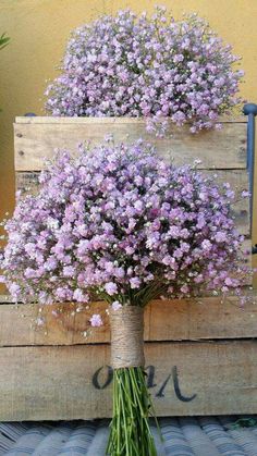 a bunch of flowers sitting on top of a wooden crate next to another box filled with purple flowers