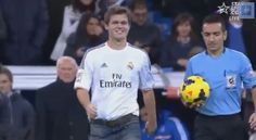 a man holding a soccer ball on top of a field next to another man with a blue shirt