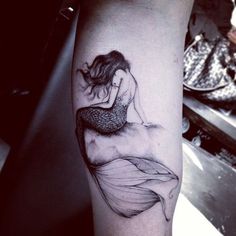 a woman sitting on top of a wave tattoo