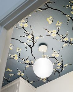 the ceiling in this bathroom is painted with flowers and branches on it, while the light fixture