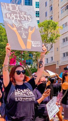 a woman holding up a sign in the middle of a crowd