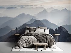 a bed sitting in front of a wall with mountains on it's sides and a bench next to it