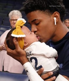 a man holding a baby in his arms while wearing a yellow hat and white shirt