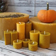 several candles sitting on top of a table next to a cake with a pumpkin in the background