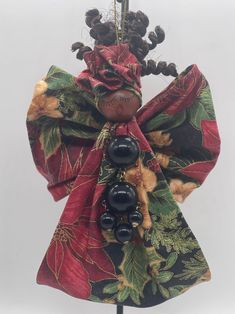 a red and green scarf with beads hanging from it's center piece, on top of a wooden stand