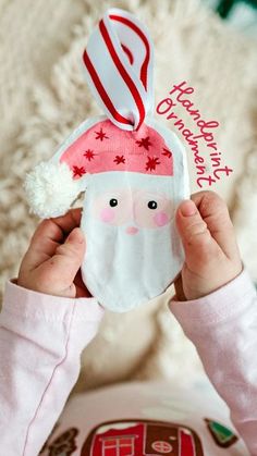 a child holding up a santa clause ornament to show it's face