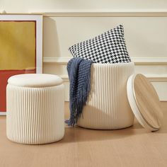 two white stools sitting on top of a hard wood floor next to a painting