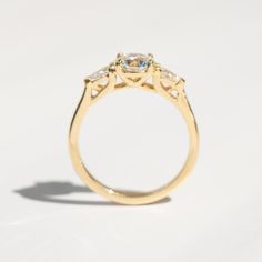 a yellow gold ring with three stones on the top and bottom, sitting on a white surface