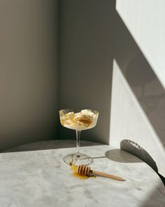 a glass filled with liquid sitting on top of a table next to a honey comb