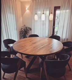 a round wooden table surrounded by black chairs