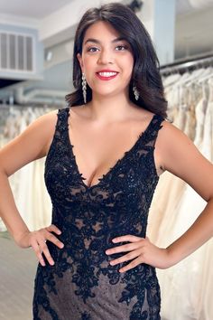 a woman in a black dress posing for the camera with her hands on her hips