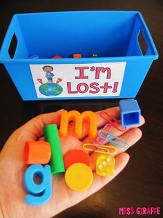 a hand holding a blue container filled with lots of magnets and plastic letters that spell out the word i'm lost