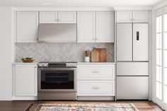 a kitchen with white cabinets and an area rug in front of the stove top oven