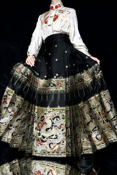 A special construction style of traditional Mamian Qun 马面裙 (horse face skirts), with 8 pairs of pleats on each side to create the most dramatic and flowy skirt possible. A popular skirt from the Ming Dynasty, this A-line skirt is not only comfortable, but flattering on every body type! The brocade features a fierce twisted dragon, peonies, cherry blossoms, camellias, stars, lanterns, and more. All symbols of peace, prosperity, and protection. Made from various colored threads and golden accents Costume Full Gathered Skirt, Traditional Black Skirt For Festive Season, Traditional Black Skirt For Festive Occasions, Costume Full Skirt With Gathered Details, Traditional Black Flowy Skirt, Traditional Harem Skirt For Festivals, Traditional Red Flared Maxi Skirt, Traditional Black Lined Skirt, Traditional Festival Flared Maxi Skirt