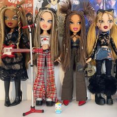 three dolls are standing next to each other in front of a wall with posters on it