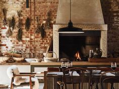 a kitchen with brick walls and an oven in the center, surrounded by wooden chairs