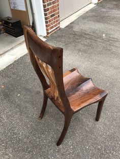 a wooden chair sitting on the ground next to a garage