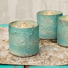 three tea light candles sitting on top of a wooden table next to a blue vase