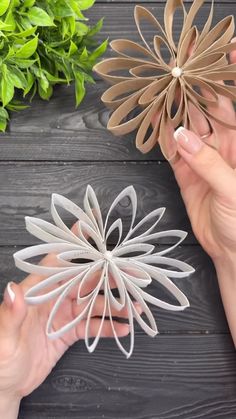 two hands holding paper flowers on top of a wooden table