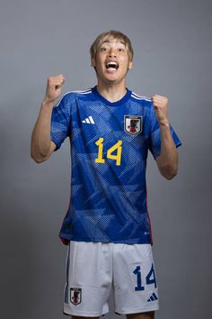 a young man in a soccer uniform holding his fist up