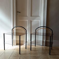 two glass tables sitting next to each other on top of a tile floor in front of a door