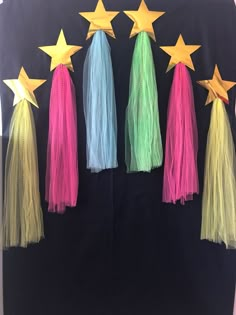 five star tassels in different colors are hanging on a black backdrop with yellow stars