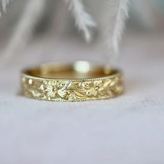 a gold wedding ring sitting on top of a white feather