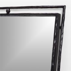 a mirror hanging on the wall with a black frame and an iron bar around it