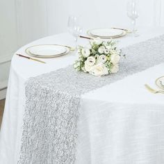 the table is set with white flowers and gold place settings