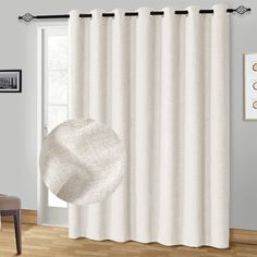 a white curtain hanging on the side of a window next to a chair and table