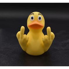 a yellow rubber duck sitting on top of a black surface with one hand up in the air