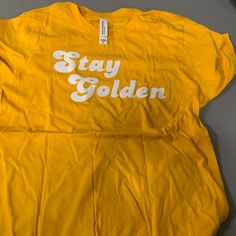 Stay Golden Tshirt Size Youth Xl Casual Tan T-shirt With Screen Print, Tan T-shirt For Spring Streetwear, Gold T-shirt With Letter Print For Summer, Sporty T-shirt For Spring Fan Merchandise, Relaxed Fit Tan T-shirt With Text Print, Casual Fan Merchandise T-shirt For Spring, Tan T-shirt With Letter Print For Spring, Gold Crew Neck Top With Logo Print, Casual Yellow T-shirt With Letter Print