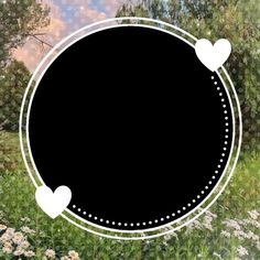 a black circle with white hearts in the middle surrounded by wildflowers and trees