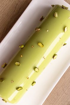 a white plate topped with a piece of cake covered in pistachio