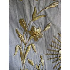 an embroidered piece with gold flowers and leaves on grey fabric, next to other decorative items