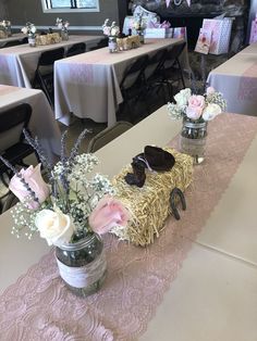 the table is decorated with pink and white flowers in mason jars, straw bales, and baby's breath