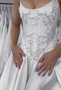 a woman in a white wedding dress is holding her hand on the back of her dress