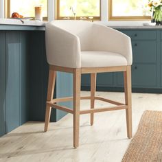 a white counter top sitting next to a wooden bar stool in a room with blue cabinets