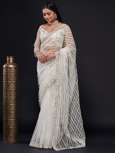 Indulge in the regal sophistication of this handpicked delicacy and stay trendy with the Glamorous White Sequin Work Net Wedding Wear Saree With Blouse. Infused with comfort and style, this saree is sure to get you noticed at any party or event. The saree is crafted from high-quality net fabric that elevates its charm and is embroidered with thread and dori work, highlighting the sequin work and giving it an elegant look.
The white saree looks gorgeous and is versatile enough to be styled in dif White Sequin Saree, Bollywood Sarees Online, Dori Work, Sequence Saree, Sequin Saree, White Saree, Party Wear Saree, Net Saree, Wear Saree