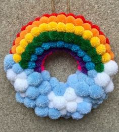 a rainbow wreath hanging on the wall with pom poms