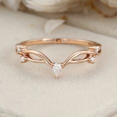 a rose gold ring with three diamonds on the top and two leaves in the middle