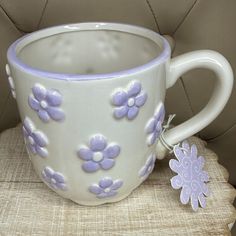 a white and purple coffee cup sitting on top of a wooden table next to a tag